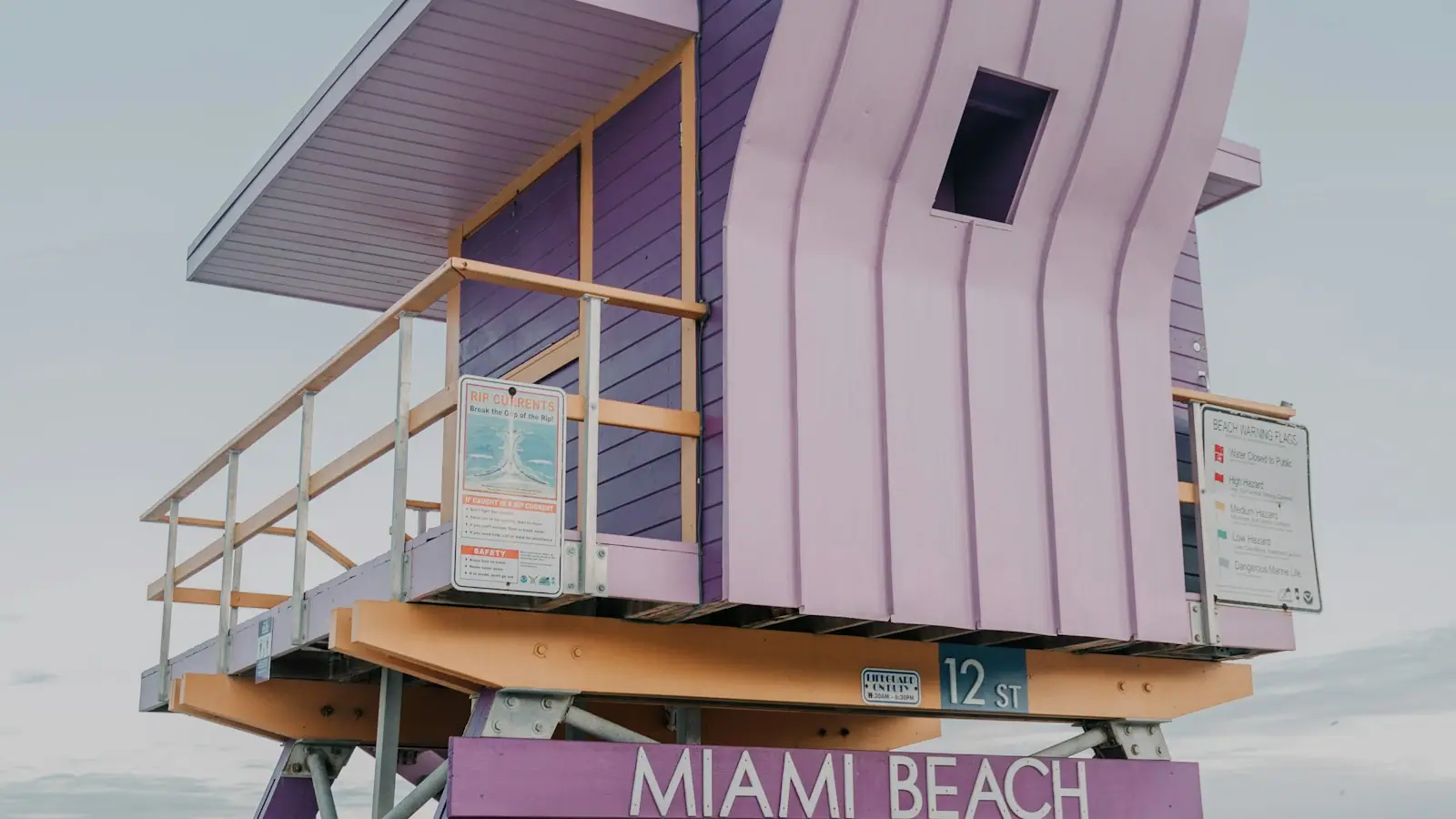 A brightly painted wooden lifeguard tower standing on the sand at Miami Beach in daylight