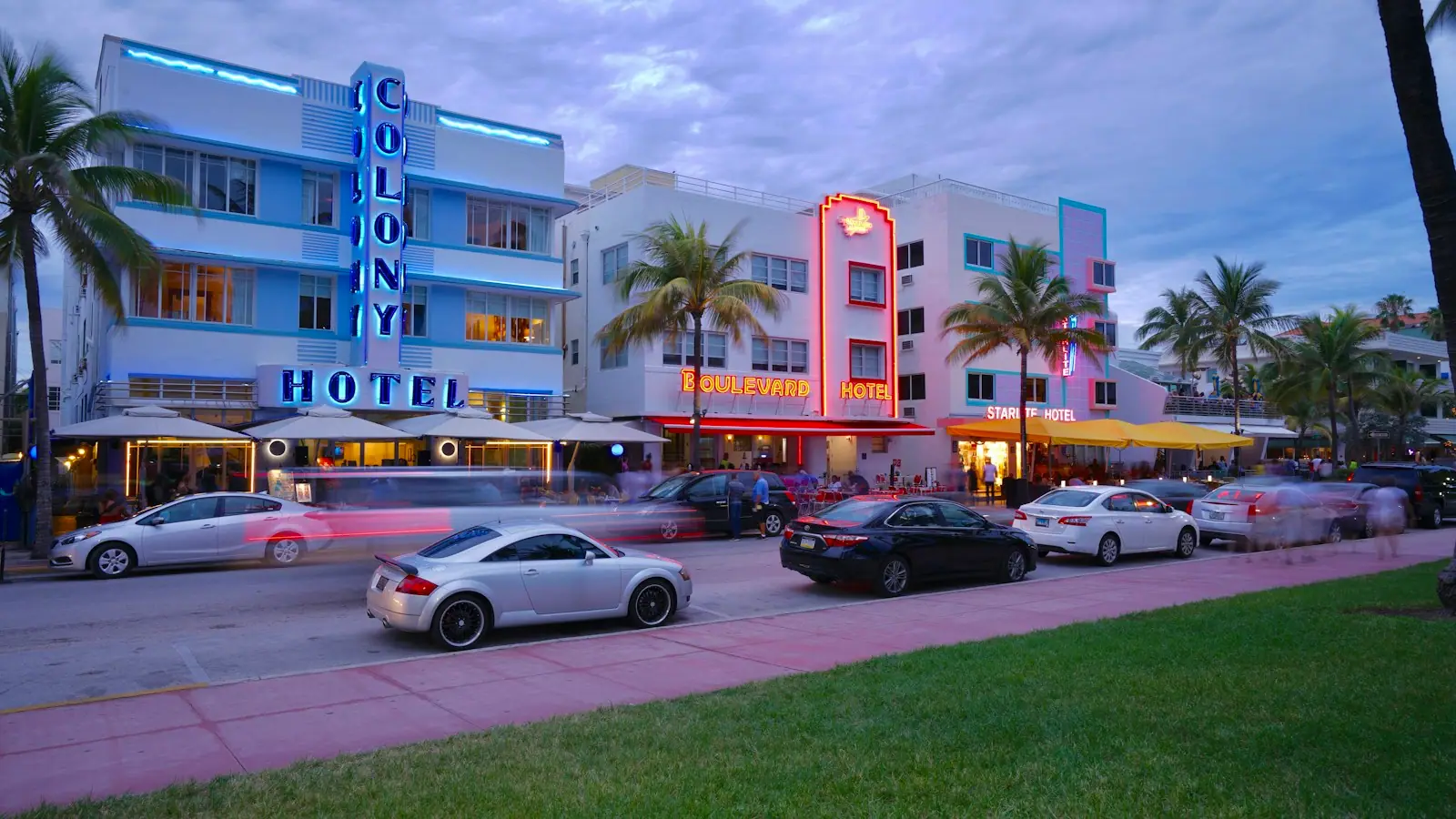 Cars parked along a kerb beside a wide Miami Beach sidewalk in daylight