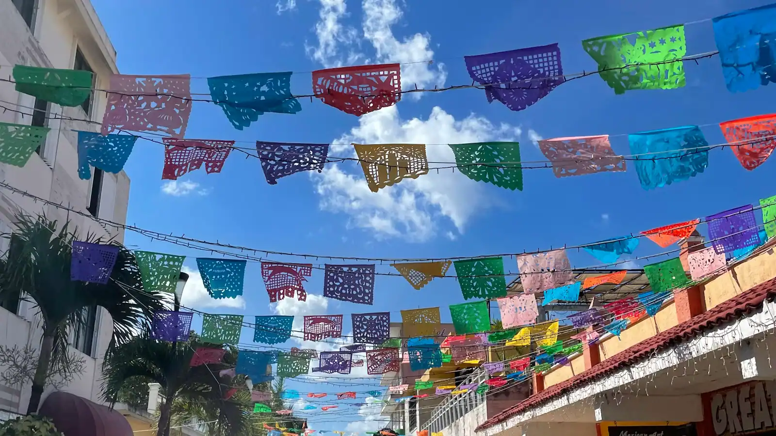 Rows of colourful cut-paper bunting strung across a sunlit street