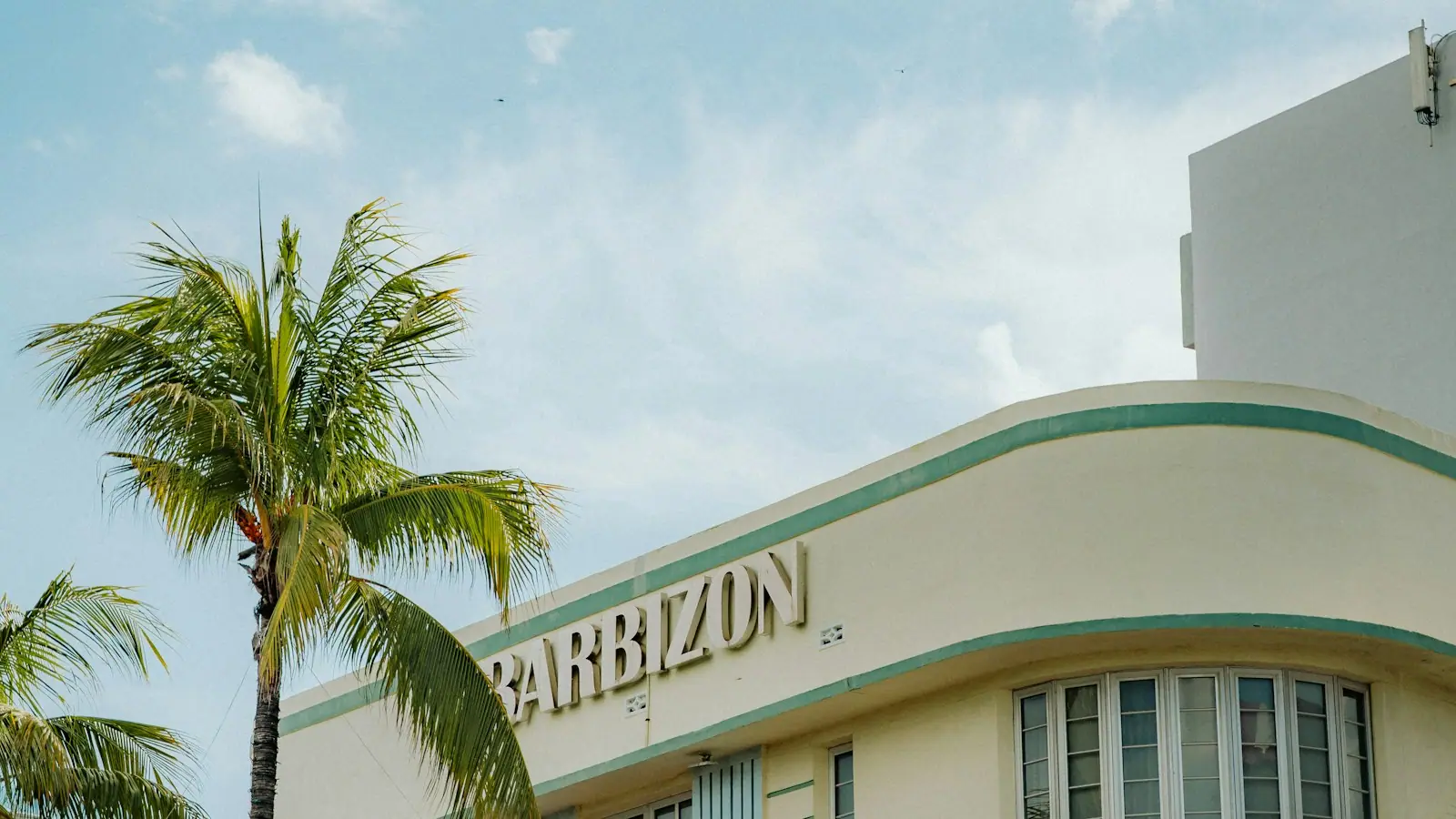 An Art Deco building and palm trees under a heavy grey cloudy sky in Miami Beach