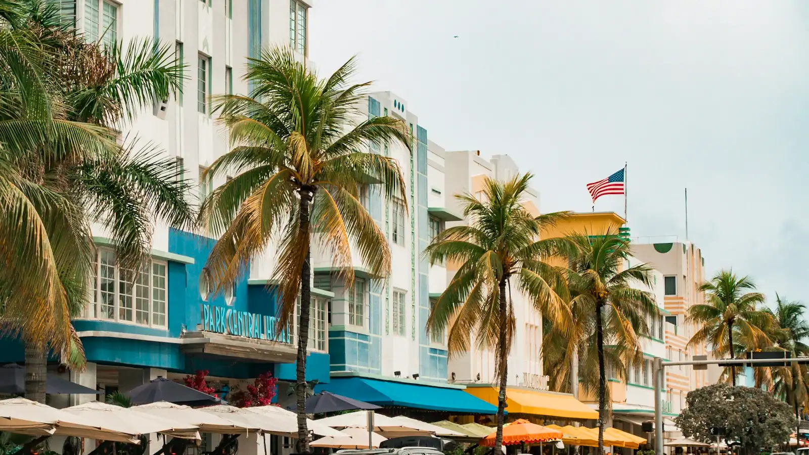 Low Art Deco buildings and palm trees lining a street in Miami Beach under bright sun
