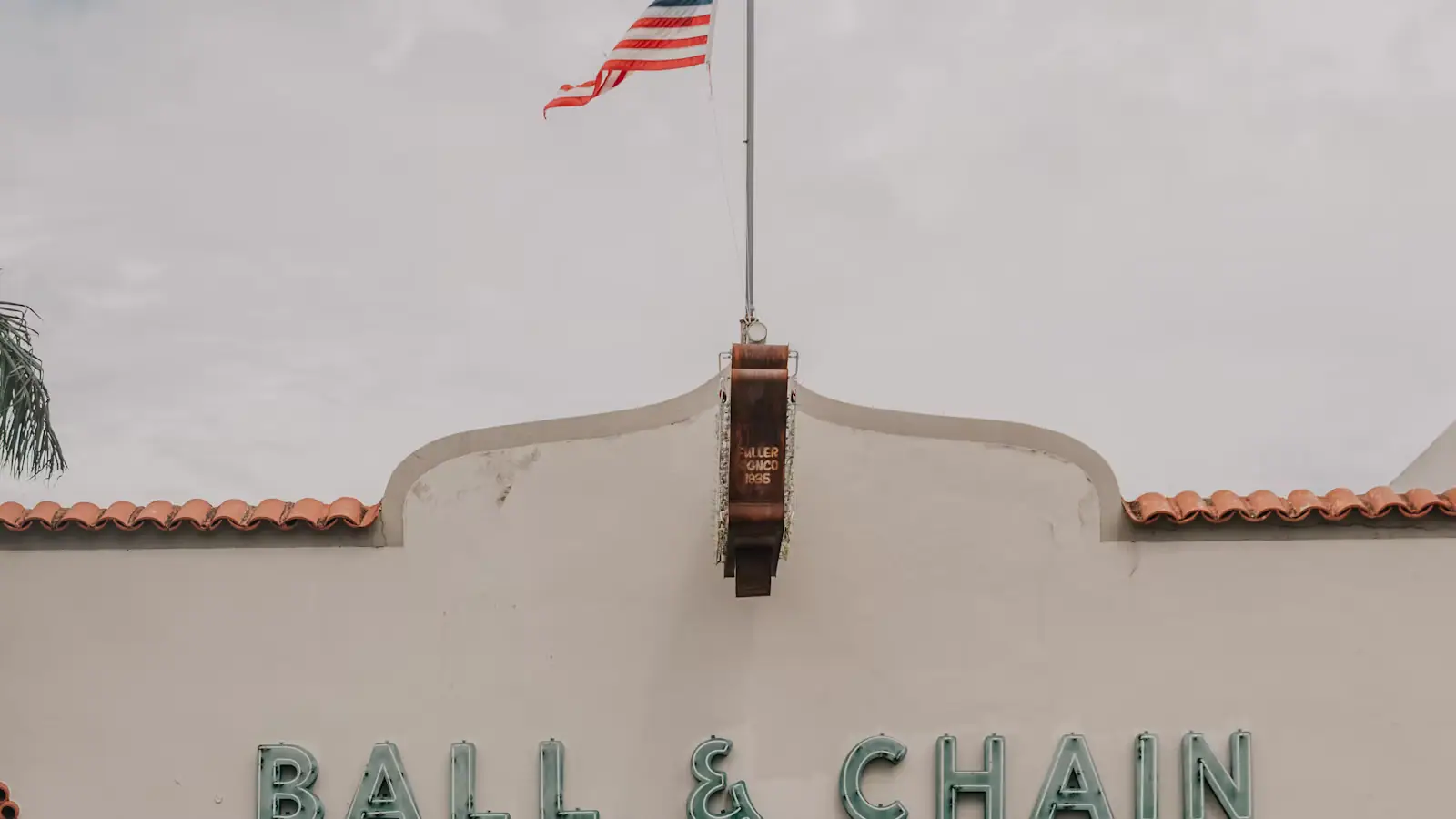 A striped awning and painted lettering above a storefront with a US flag on the wall